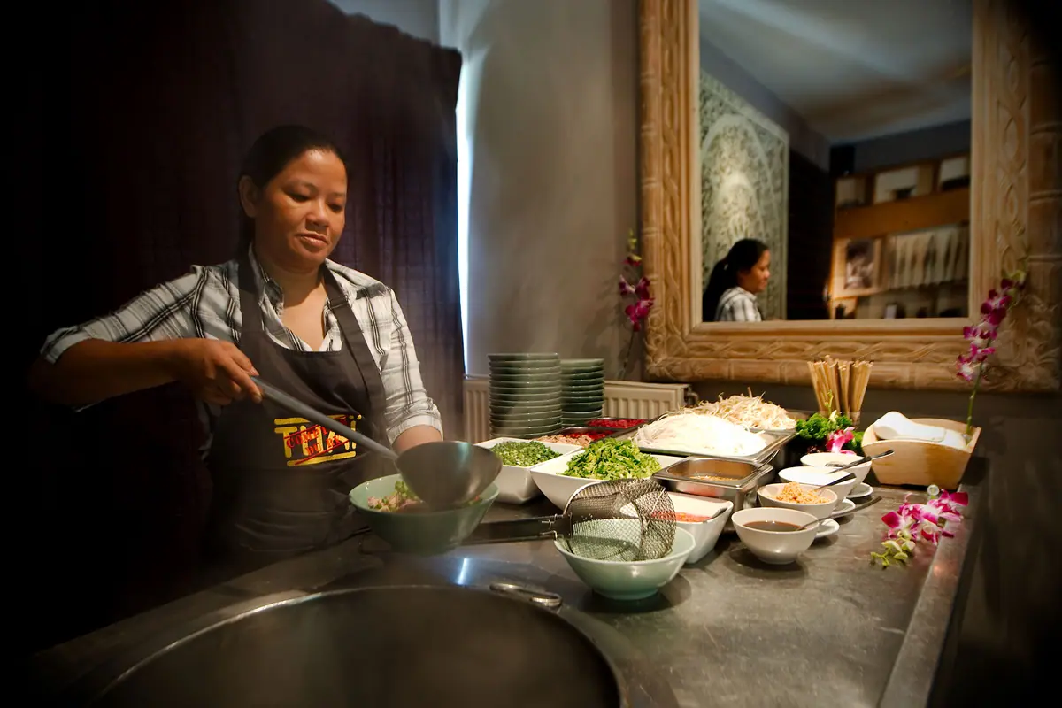 De kokkin bereidt een Thais wokbuffet tijdens een traiteurdienst