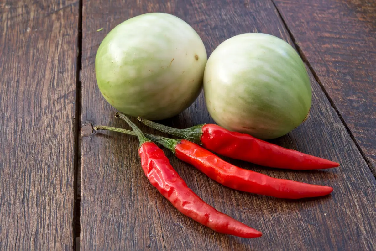 Rode pepers en Thaise aubergines op een houten plank