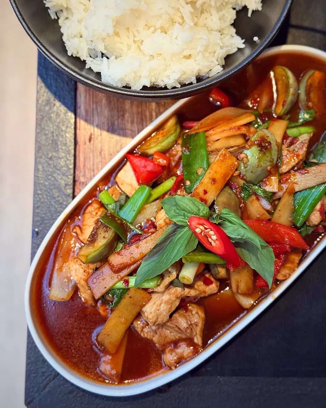 Gewokt met Thaise basilicum, bamboescheuten en peper, met een kom rijst